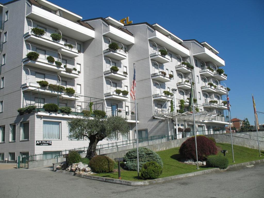 een wit appartementencomplex met een boom ervoor bij Air Palace Hotel in Leinì
