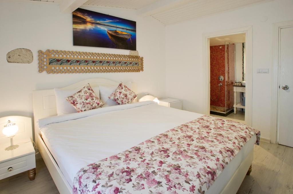 a bedroom with a white bed with a floral blanket at Lodos Butik Hotel in Alaçatı