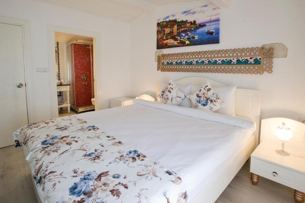 a bedroom with a large white bed with blue flowers at Lodos Butik Hotel in Alaçatı