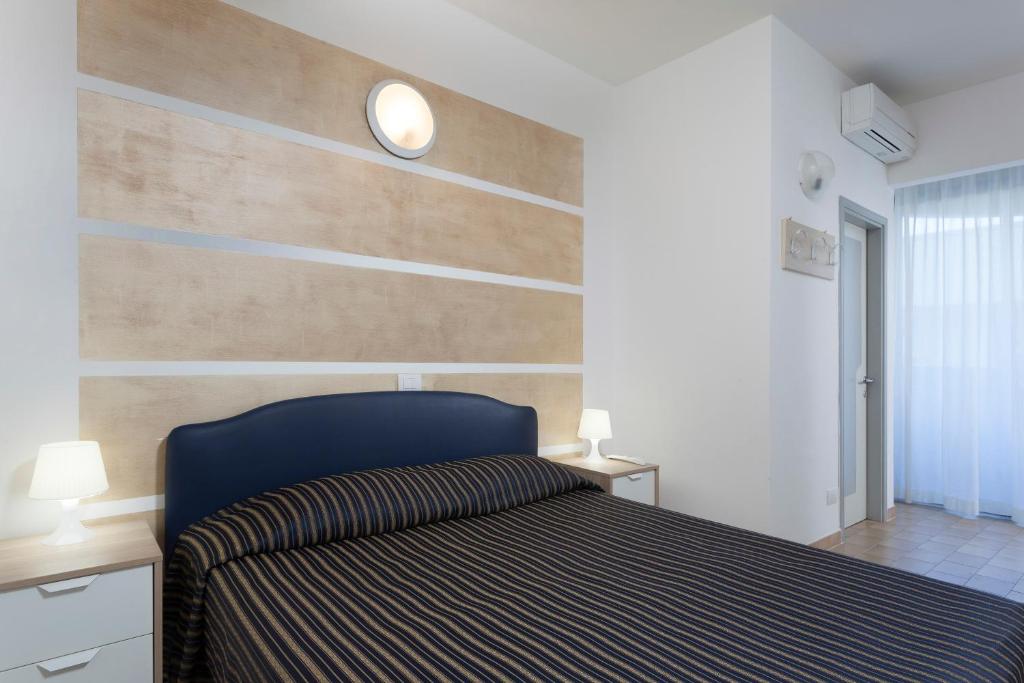 sypialnia z łóżkiem z drewnianymi akcentami w obiekcie Residenza Levante w mieście Riccione