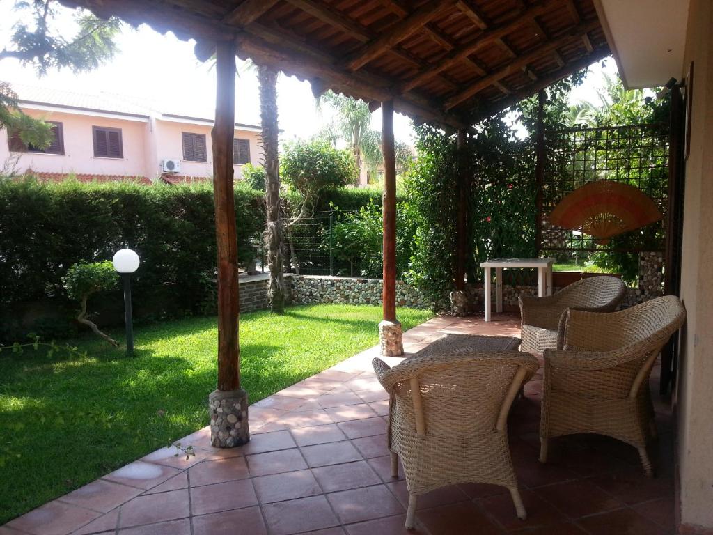 a patio with a table and chairs under a pergola at Le Ville di Porto Ada in Pizzo