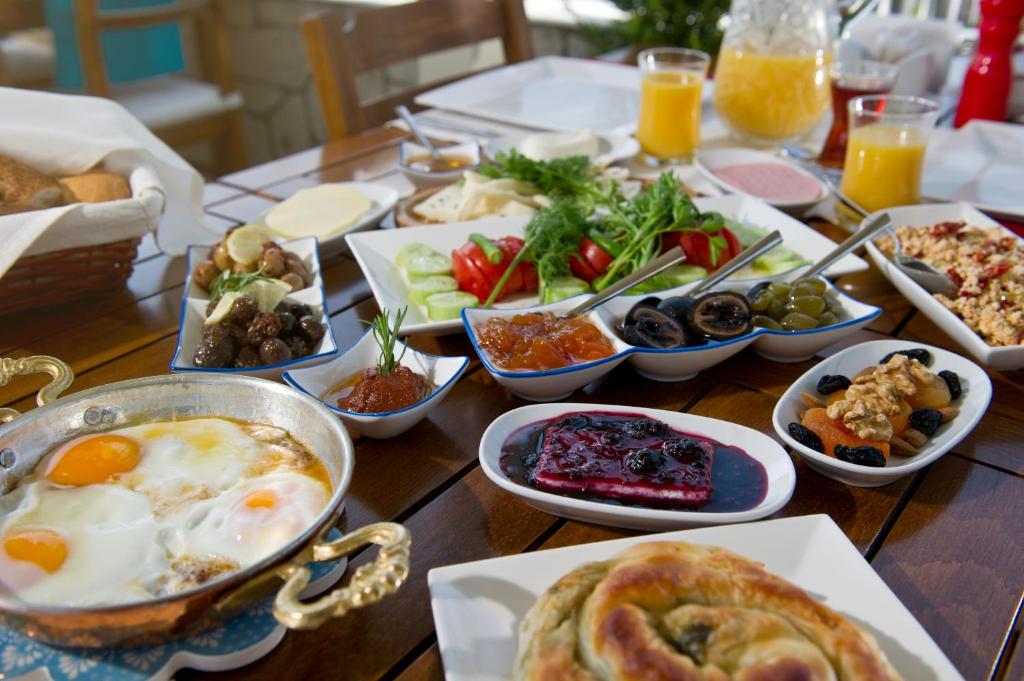 a wooden table topped with dishes of breakfast foods at Lodos Butik Hotel in Alaçatı