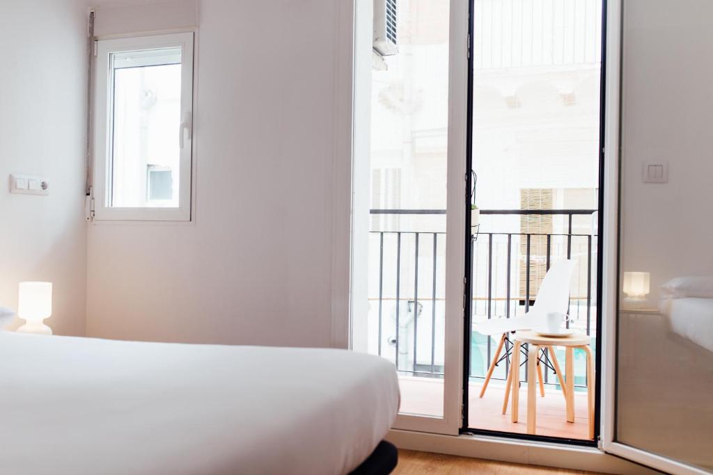 Habitación blanca con cama y balcón. en Botànic Apartaments, en Valencia