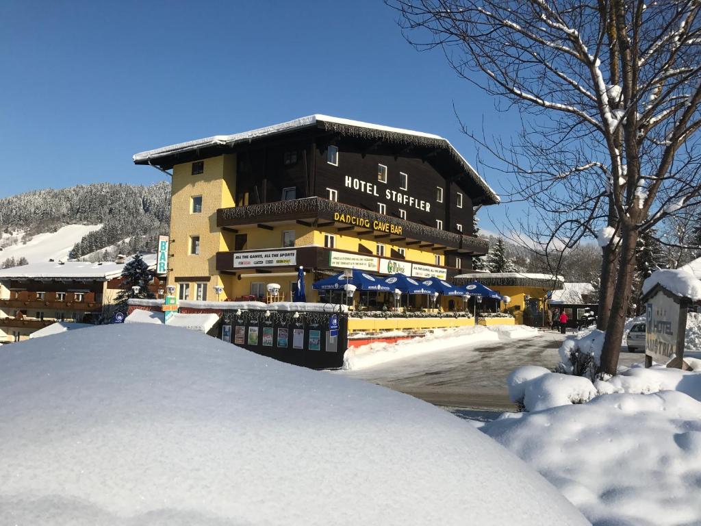 a large building with a snow pile in front of it at Hotel Staffler in Niederau