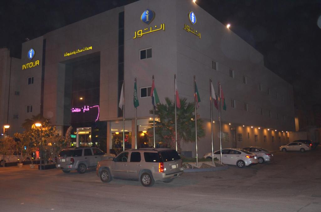 un edificio con coches estacionados fuera de él por la noche en Intour Qurtoba, en Riad