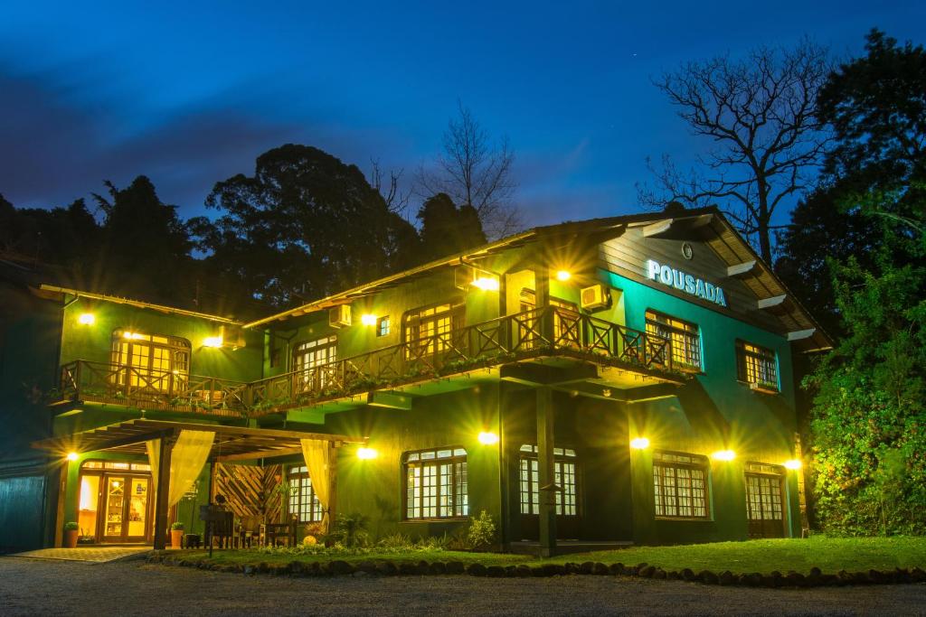 a green building with lights on it at night at Pousada Três Pinheiros in Gramado