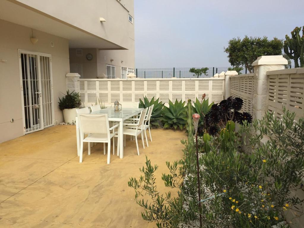 eine Terrasse mit einem Tisch, Stühlen und einem Zaun in der Unterkunft Cabo de Gata Oasis Retamar in El Toyo