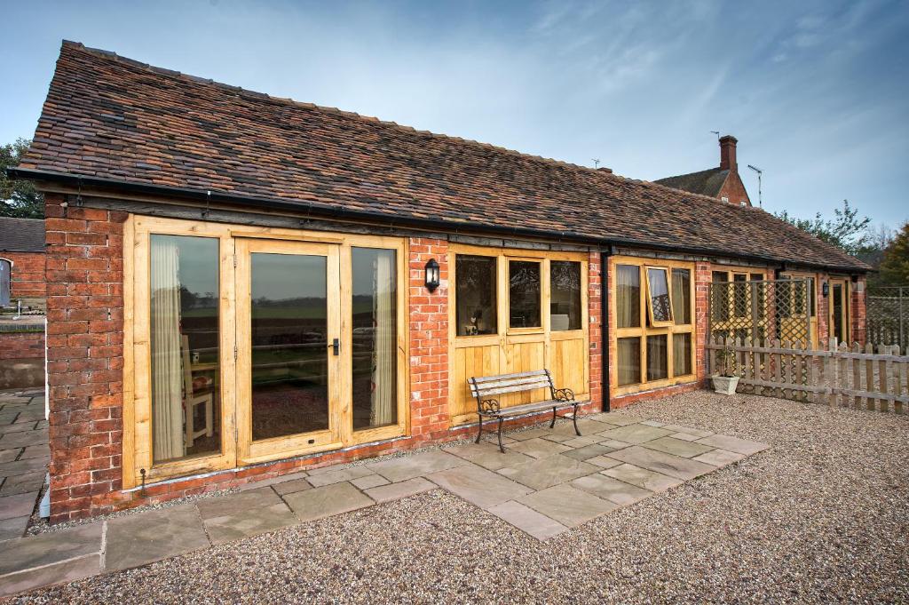 una casa con puertas de cristal y un banco en un patio en Cart Shed Cottage en Newport