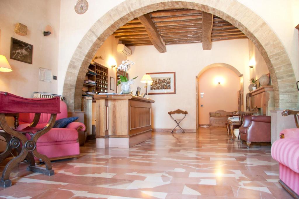 a living room with an archway and pink furniture at Hotel Porziuncola in Assisi