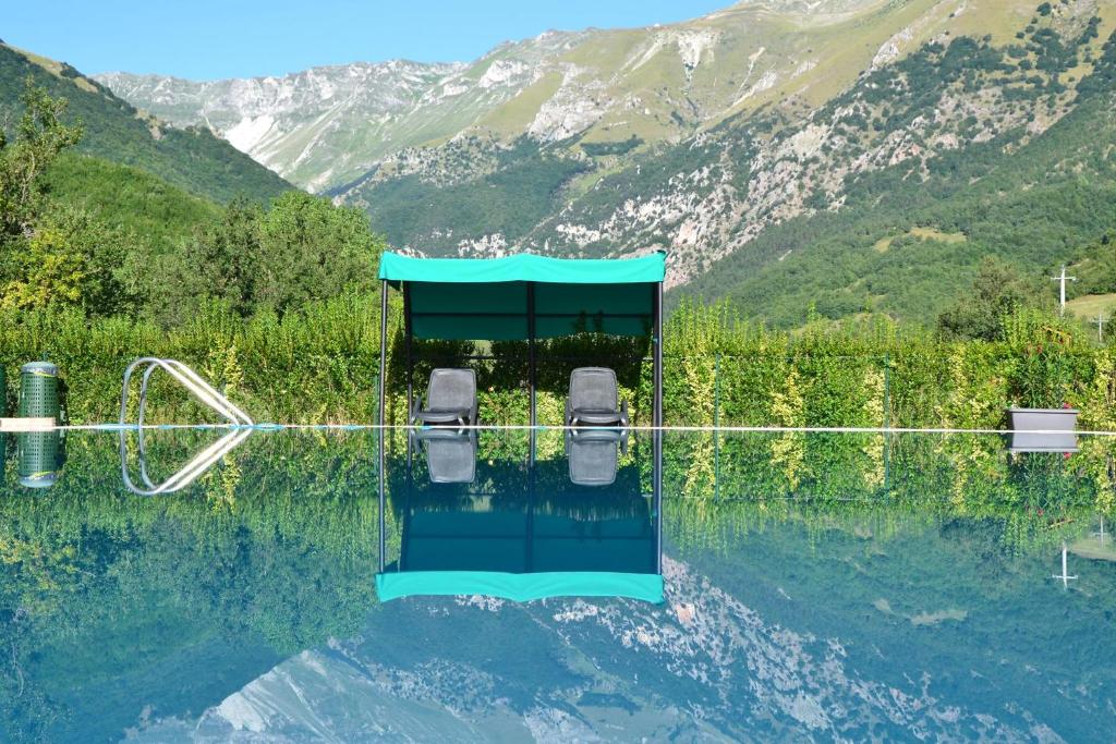 una piscina d'acqua con due sedie di fronte a una montagna di La Baita di Pilato a Montemonaco