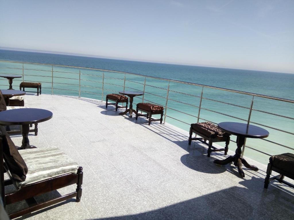 uma varanda com mesas e cadeiras e o oceano em S&K Dotro em Costinesti