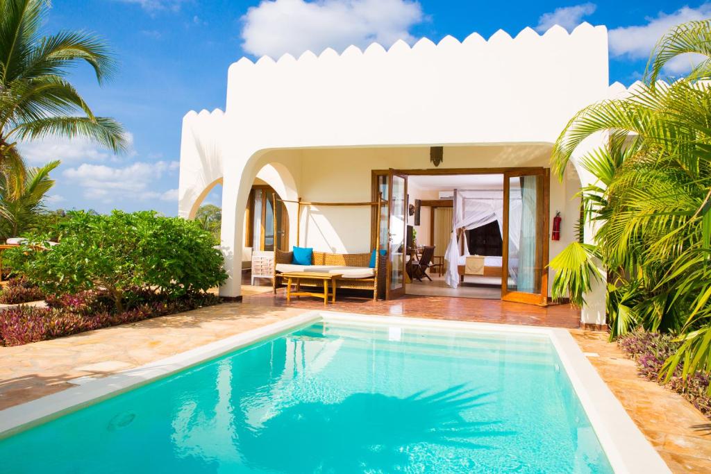 a swimming pool in front of a villa at Fruit & Spice Wellness Resort Zanzibar in Kizimkazi