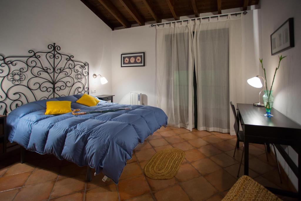 a bedroom with a bed with a blue comforter and a desk at La Mina Rural Casas con encanto in La Isabel