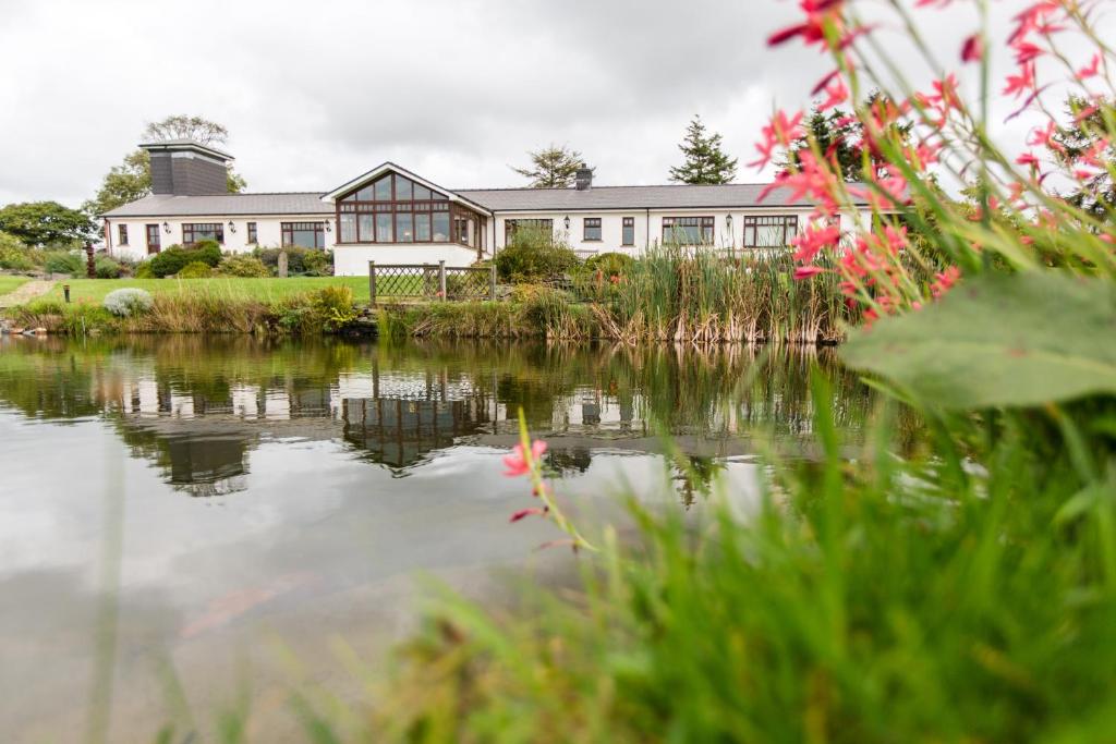 a house with a pond in front of it at Ael y Bryn Luxury B&B, North Pembrokeshire in Eglwyswrw