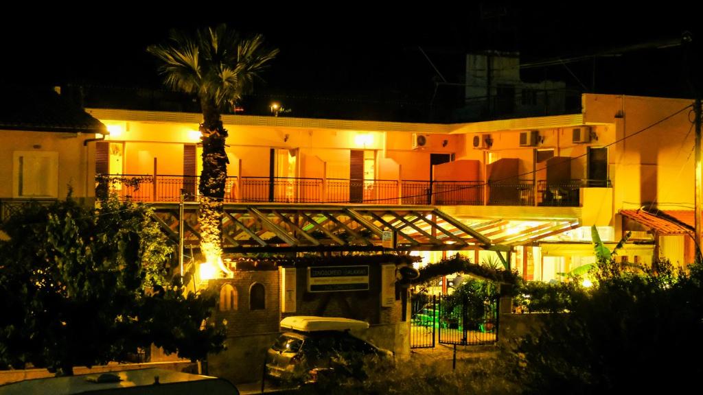 a building with a palm tree in front of it at night at Hotel Galaxias in Áyioi Pándes