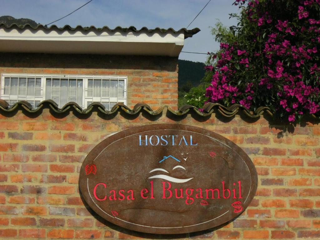 un cartello su un edificio di mattoni con un cartello per un pacco di bara dell'ospedale di Hostal Bugambil a Sopó