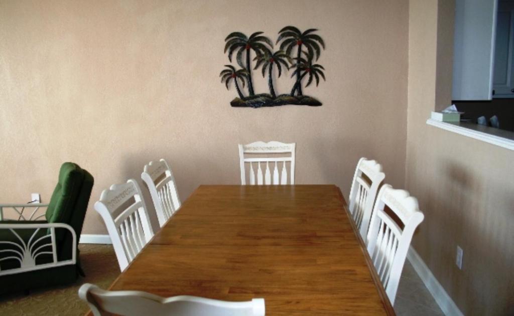 einen Esstisch mit weißen Stühlen und Palmen an der Wand in der Unterkunft Club Regency at Regency Towers in Myrtle Beach