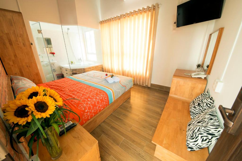 a room with a bed and a table with a vase of sunflower at Ana's House in Nha Trang