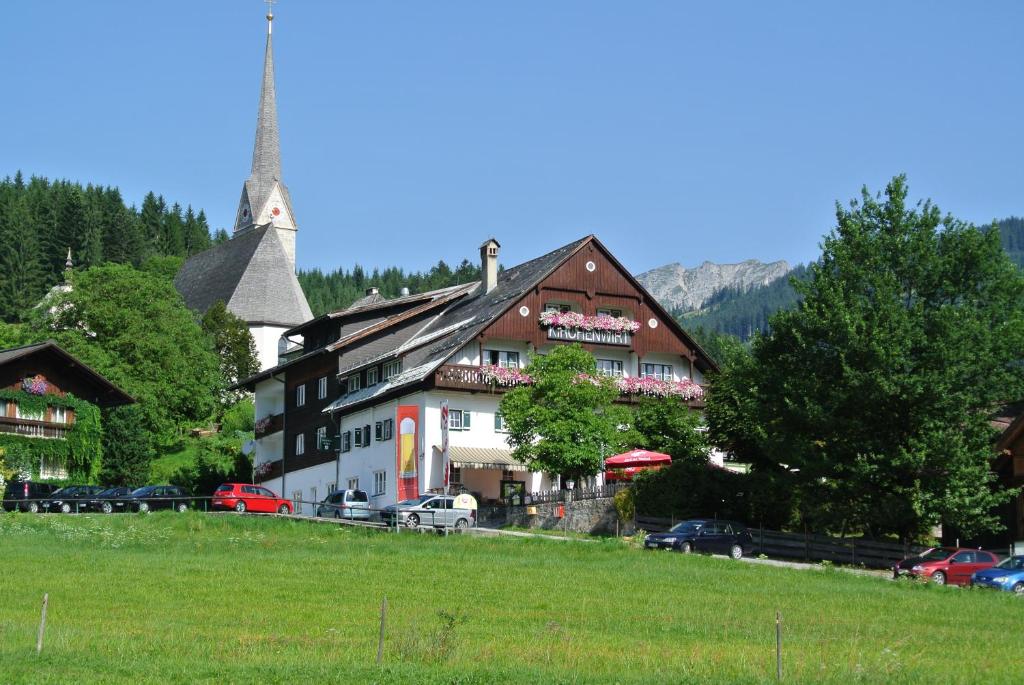 een gebouw op een heuvel waar auto's voor geparkeerd staan bij Kirchenwirt Gosau in Gosau