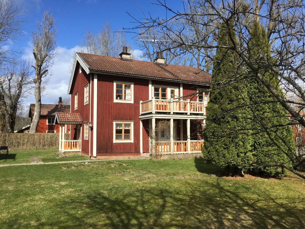 ein großes rotes Haus mit einer Terrasse auf einem Hof in der Unterkunft Hallagårdens B&B in Vintrosa