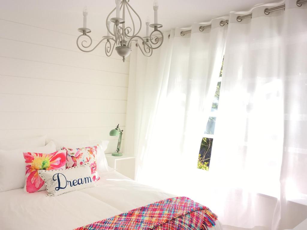 a bedroom with a bed with a chandelier and a window at Belle Maison Auprès De La Mer in Sidney