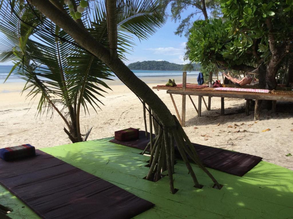 a green surfboard on a beach with a palm tree at Phayam Coconut Beach Resort in Ko Phayam