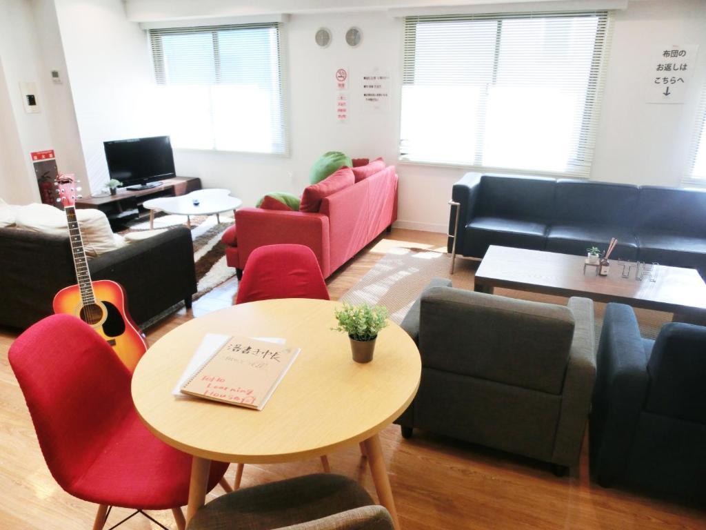 ein Wartezimmer mit einem Tisch, Stühlen und einer Gitarre in der Unterkunft Guesthouse TOHO in Nagoya