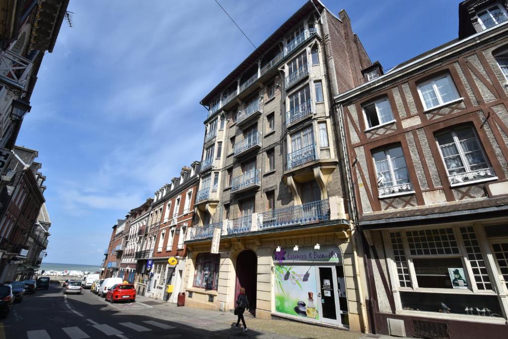 a woman walking down a street in front of a building at Ets Levillain-Hotel les Caletes in Le Tréport