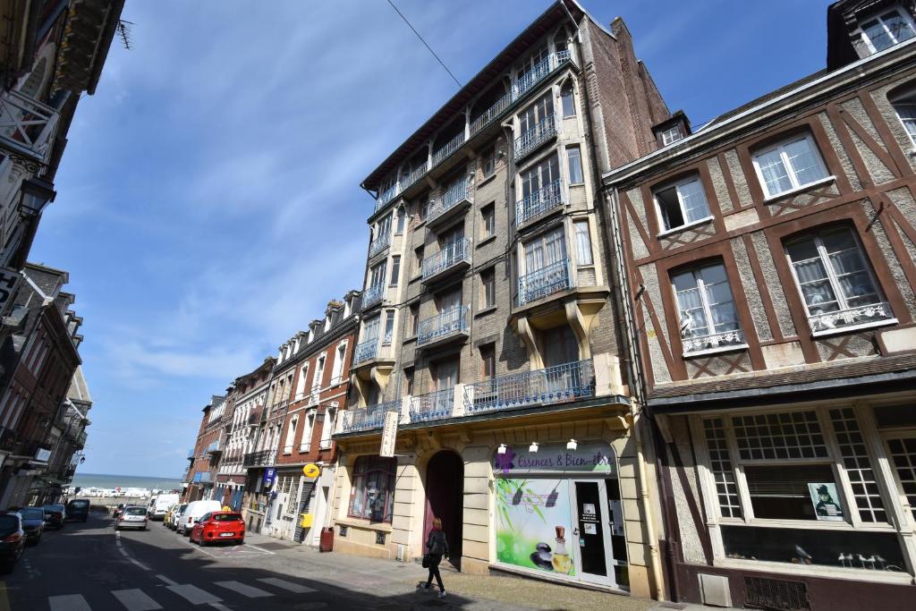 une femme marchant dans une rue devant un bâtiment dans l'établissement Ets Levillain-Hotel les Caletes, au Tréport