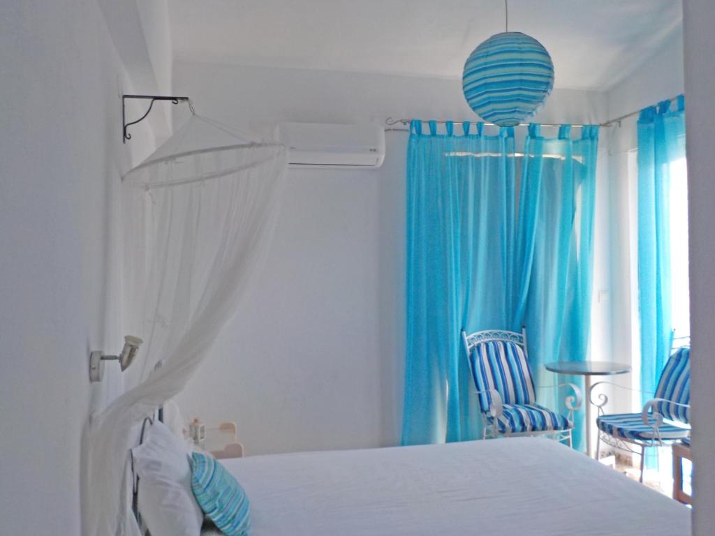 1 dormitorio con cama blanca y cortinas azules en Vivian Studios, en Ialisos