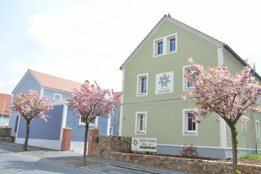 a building with flowering trees in front of it at Pension Kalinde in Weinböhla