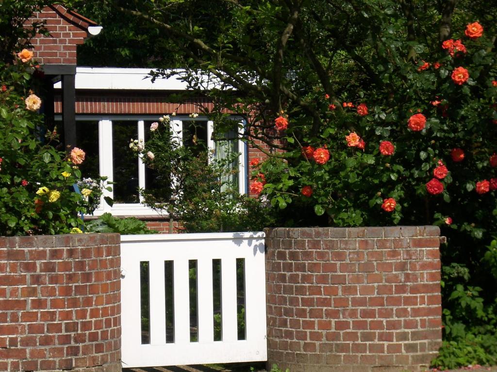 a white fence in front of a house with roses at Villa Ludwig Fewo in Otterndorf