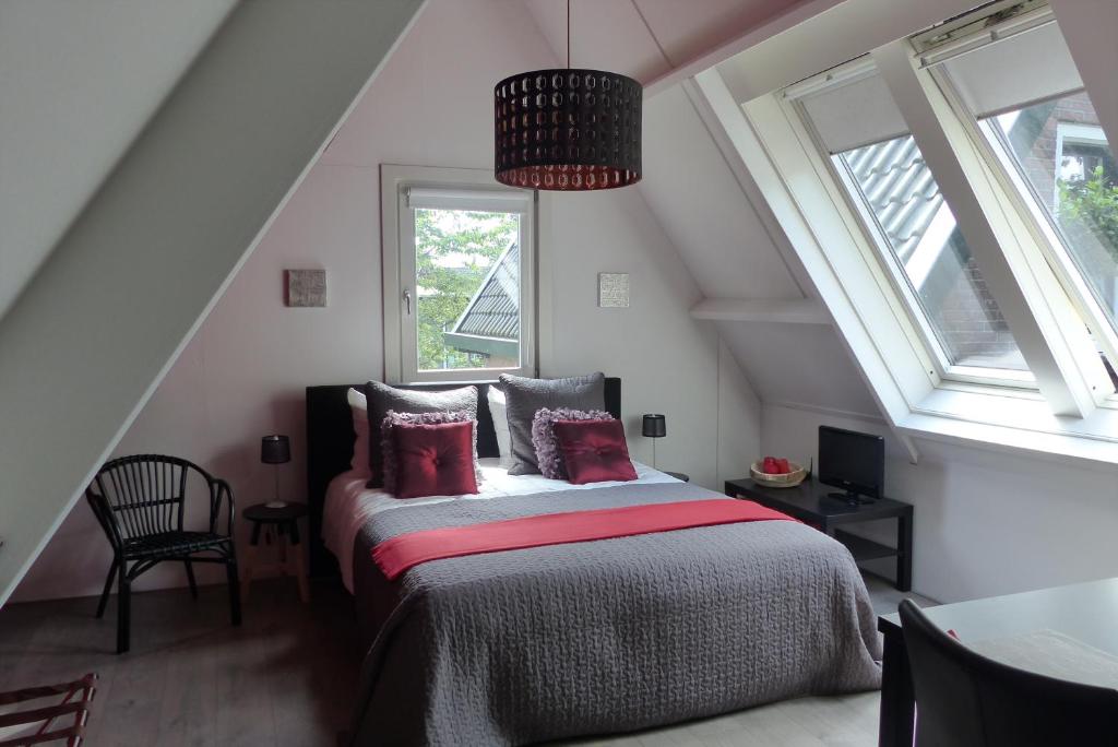 a bedroom with a bed in a attic with windows at B&B Onder de rode beuk in Dieren