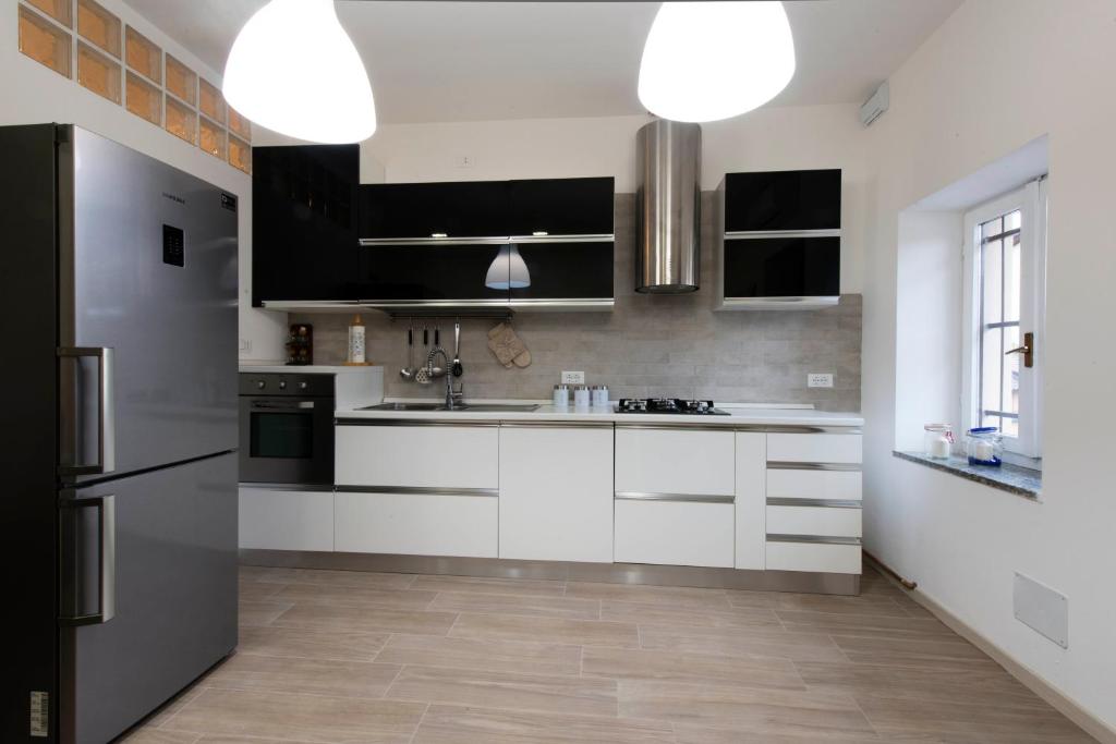 a kitchen with white cabinets and black appliances at Monza Park Apartment in Monza