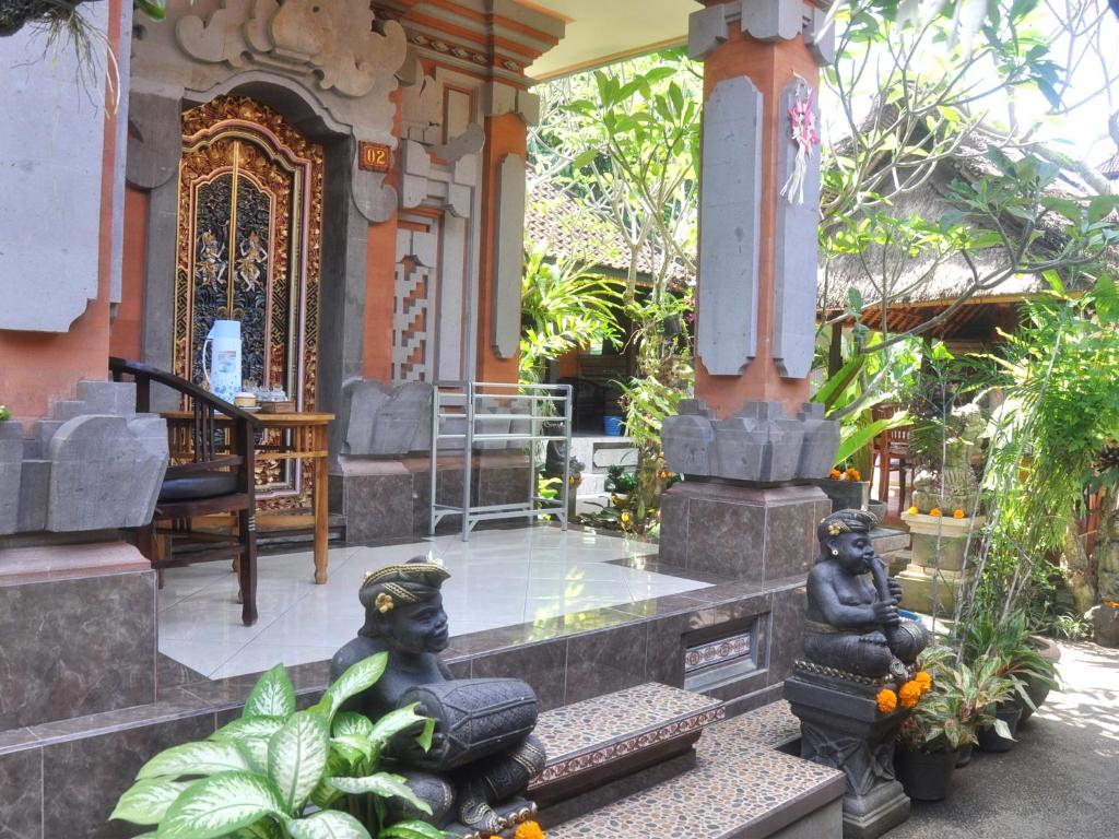 a porch of a house with statues in front of it at Depa House in Ubud