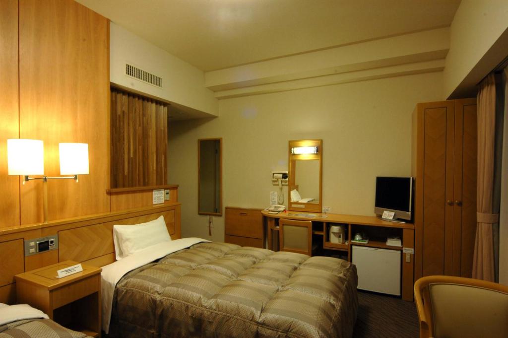 een hotelkamer met een bed en een televisie bij Hotel Route-Inn Kushiro Ekimae in Kushiro