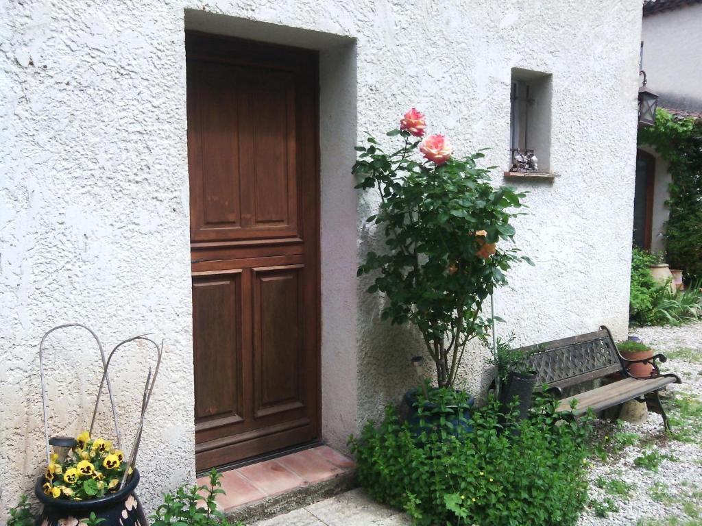 eine Tür zu einem Gebäude mit einer Bank und Blumen in der Unterkunft Chambres d'hôtes La Fouquette in Les Mayons