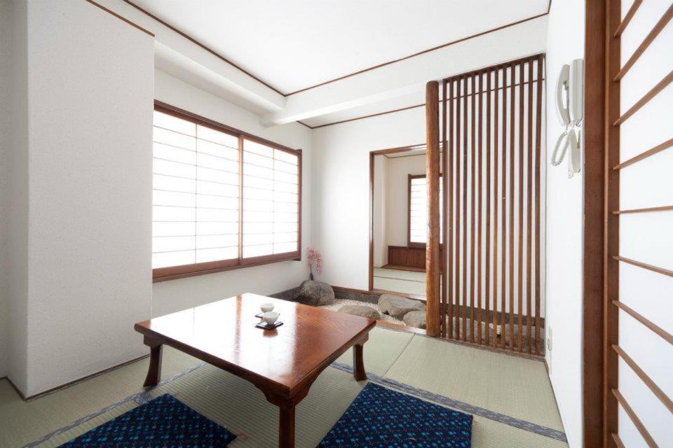 ein Wohnzimmer mit einem Tisch und ein Zimmer mit einem Hund in der Unterkunft Shin Okubo Sekitei in Tokio