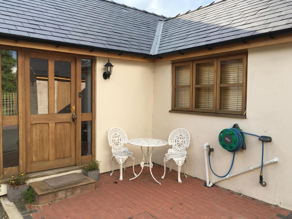 a patio with a table and chairs next to a house at Maesbury Riverside in Oswestry