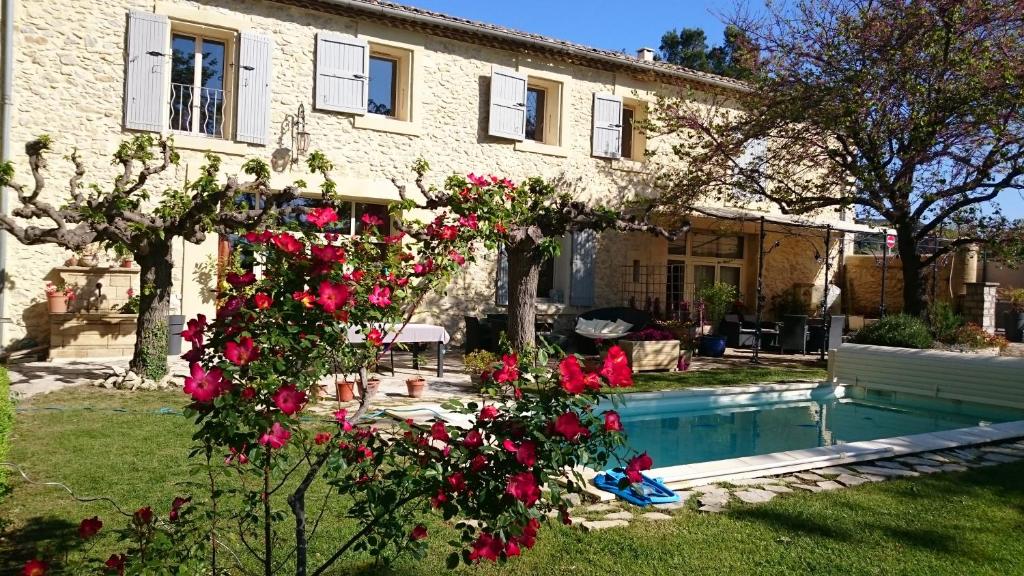 ein Haus mit einem Pool und roten Rosen in der Unterkunft Au Mas de Marie in Lédenon