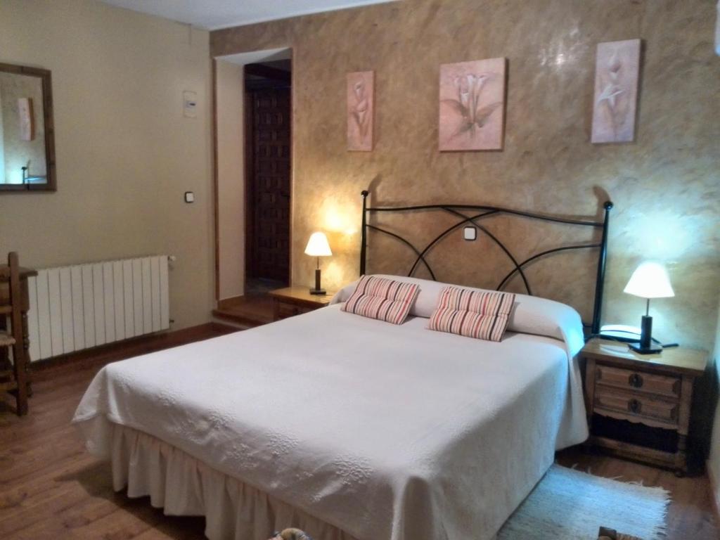a bedroom with a large bed with two pink pillows at Hostal Chinchon in Chinchón