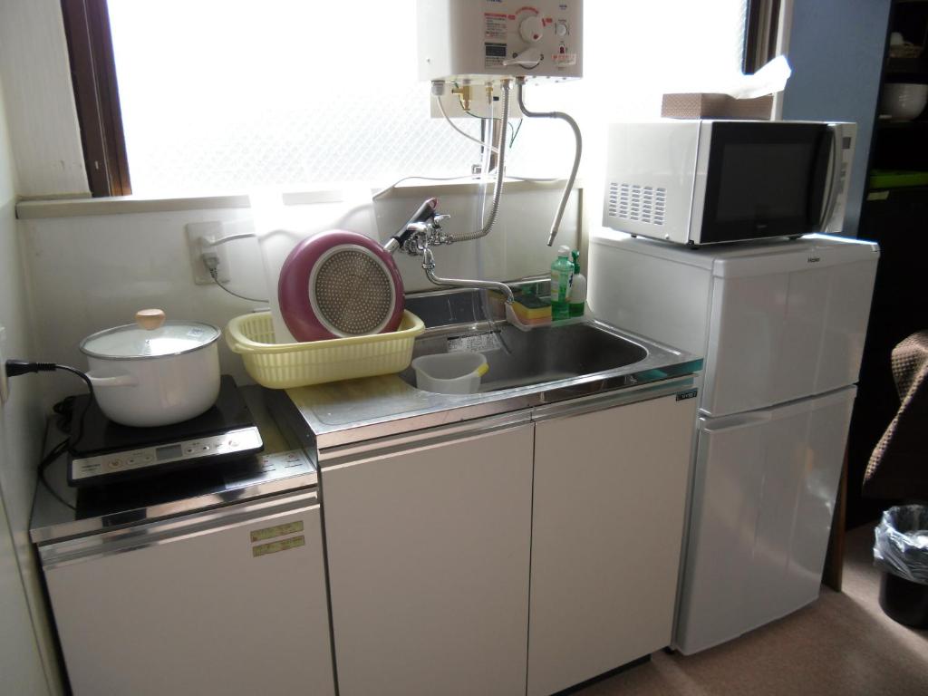 una piccola cucina con lavello e microonde di Shin Okubo Sekitei a Tokyo