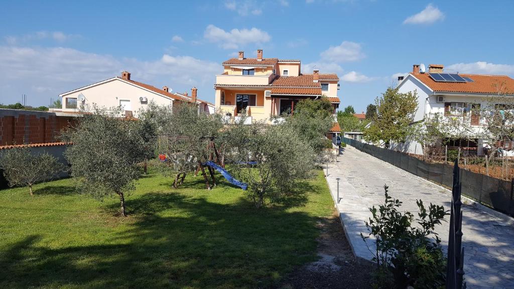 a view of a yard with trees and a house at Apartmani Viktorija in Fažana