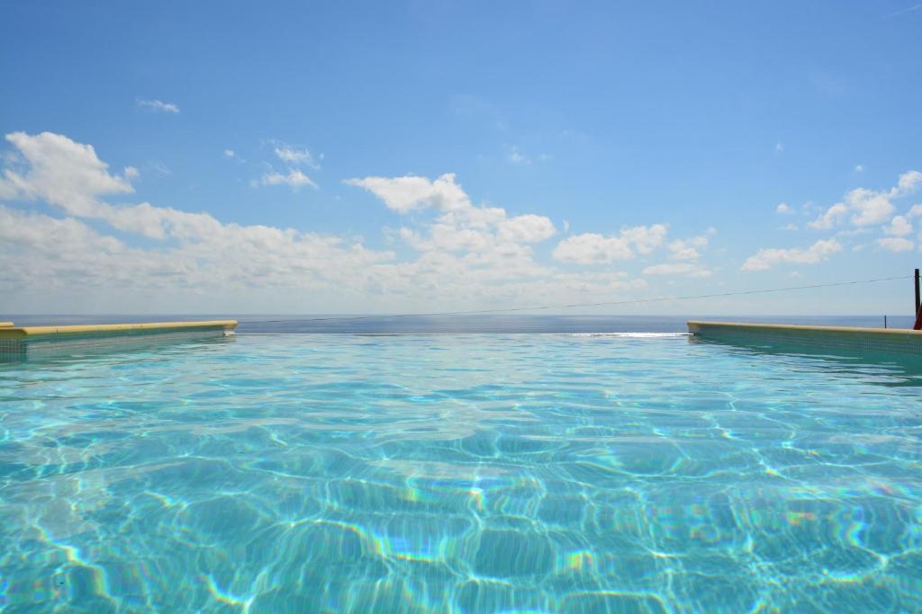 uma piscina de água com um céu azul e nuvens em Villa Nemo em Riva Ligure
