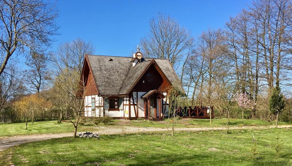 a small house with a roof on a green field at Dom Majówka i Apartamenty Bartoszówka i Michałówka in Karwieńskie Błoto Drugie