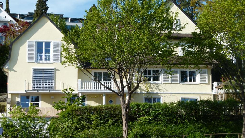 ein weißes Haus mit einem Baum davor in der Unterkunft Ferienwohnung Bodensee in Überlingen