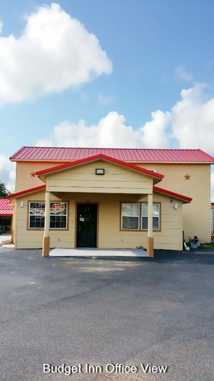 a yellow building with a red roof at Budget Inn in Hallettsville