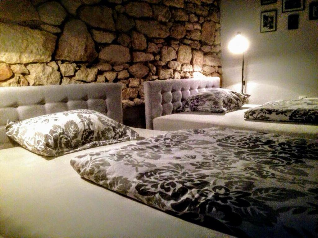 two beds in a room with a stone wall at Hostel Musala in Mostar
