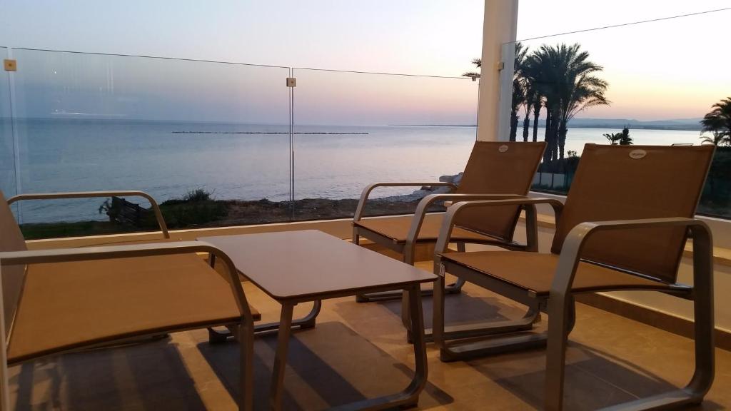 Periyiali Beach Sunset Suite A7 في بريفوليا: غرفة بها كراسي وطاولة وإطلالة على المحيط