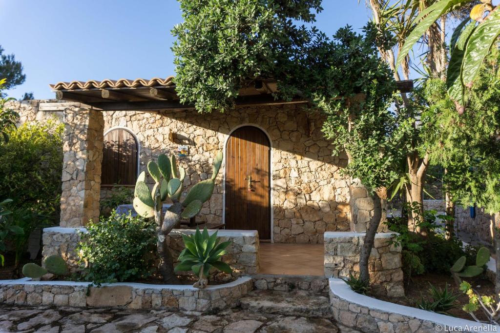 Casa de piedra con puerta de madera en un patio en Dammusi del Sole en Lampedusa